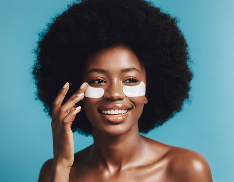Smiling Black Woman with Afro Hair Applying White Under Eye Treatment Patches