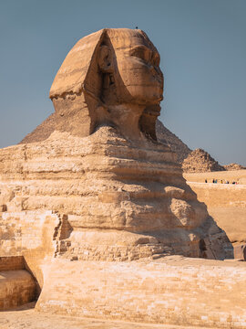 View of the Great Sphinx of Giza with the pyramid in the background under a clear blue sky in Al Haram, Giza Governorate, Egypt.