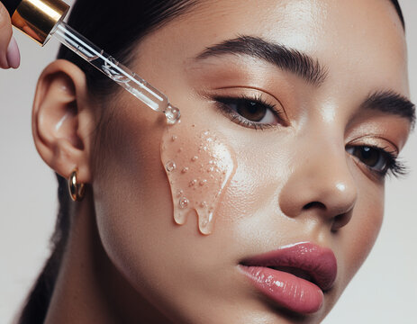 Model applying hydrating liquid serum to face with glass pipette dropper