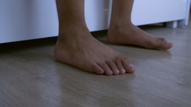 Close-up shot of man getting off the bed and stepping his feet down. Stock video of a man getting off the bed and walking towards the door after stepping down
