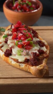 Close-up of Mexican Molletes topped with chorizo, cheese and salsa pico de gallo