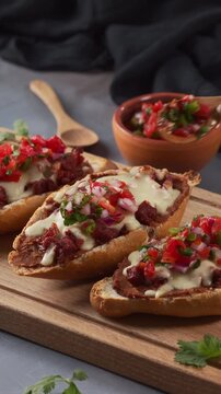 Preparing a cheese and chorizo Mexican mollete with pico de gallo on top with a wooden spoon