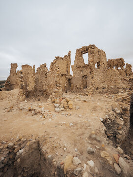 View of the ancient ruins of the Amon Temple with weathered mud-brick walls and stone structures under an overcast sky in Siwa, Marsa Matrouh Governo, Egypt.