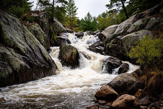 Powerful Wisconsin Waterfall Cascading Over Moss-Covered Rocks Amidst a Lush Forest Landscape