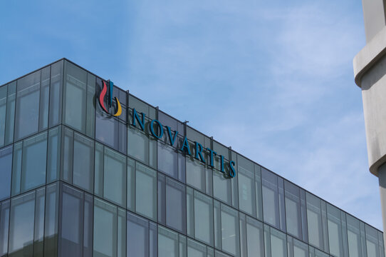 Novartis pharmaceutical company logo sign on modern glass office building facade