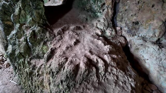 Xemxija, Malta 29.07.2026 - Heritage trail, Roman Baths. Ancient cave walls show rugged textures and earthy tones. Narrow passageway reveals distant, dimly lit chambers. Stone surfaces bear signs of a