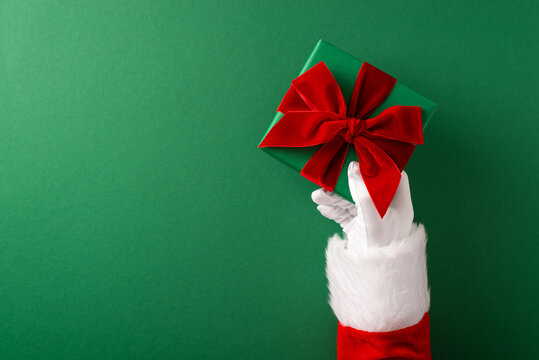 Merry Christmas and Happy New Year from Santa Claus holding a wrapped green present with red bow