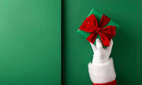 Merry Christmas and Happy New Year from Santa Claus holding a green wrapped gift with red bow