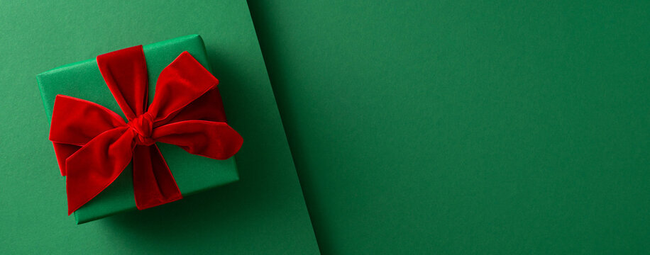 Merry Christmas and Happy New Year greeting with a green gift wrapped in red velvet bow from Santa Claus