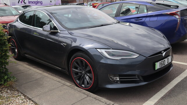 Norwich, United Kingdom &ndash; June 8, 2026: Everyday retail and consumer life Sleek tesla model s electric car with custom red rimmed wheels parked in a lot