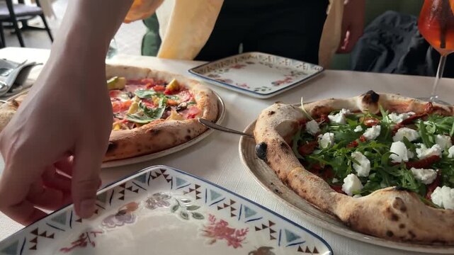 Male hands serving slice of artichoke pizza with spatula and fork onto plate at restaurant table, gourmet Italian cuisine, shared dining and authentic food experience