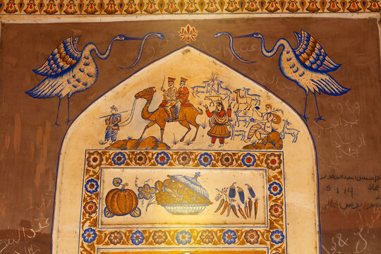 View of traditional mural paintings featuring camel riders and floral motifs inside the historic Jamali tombs in Dadu, Sindh, Pakistan.
