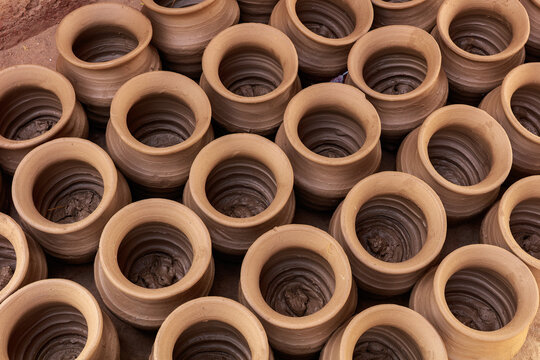 View of handmade clay pots arranged in rows for drying in the sun in Thatta, Sindh, Pakistan.