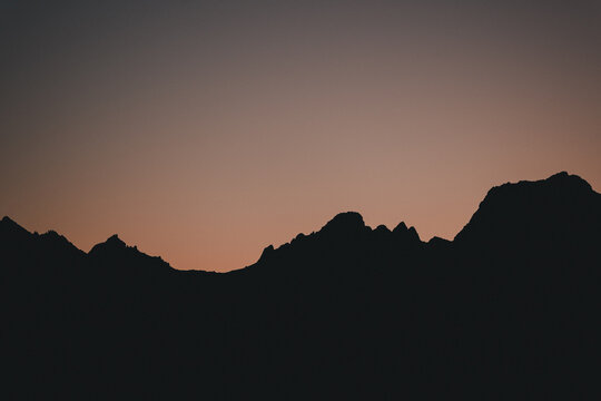 Holmstad, Nordland, Norway - 31 August 2025: View of the silhouetted mountain range against a soft sunset sky in the Nordland region.