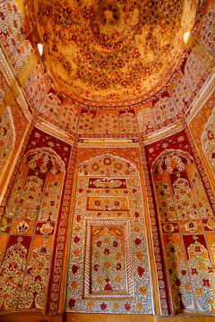 View of the intricate, colorful floral wall paintings and decorated dome inside a historic tomb in Ghaibi Dero, Sindh, Pakistan.