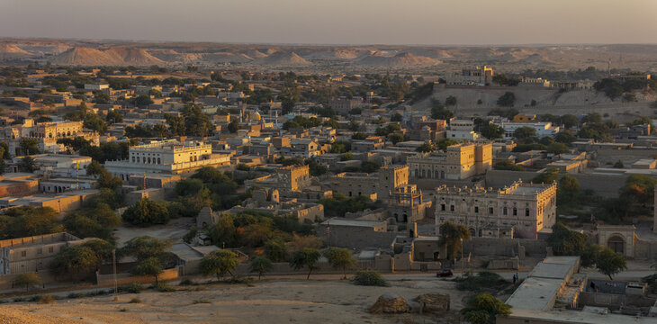 View of the historic town of Kot Diji with traditional architecture, stone buildings, and arid desert landscape under the warm light of the golden hour in Kot Diji, Sindh, Pakistan.