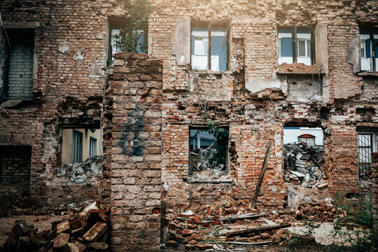 Abandoned brick building facade with collapsed walls and rubble, urban decay scene for demolition, redevelopment, housing crisis, structural damage and disaster recovery.