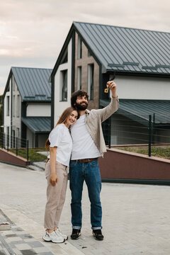 Happy couple holding house keys standing new home