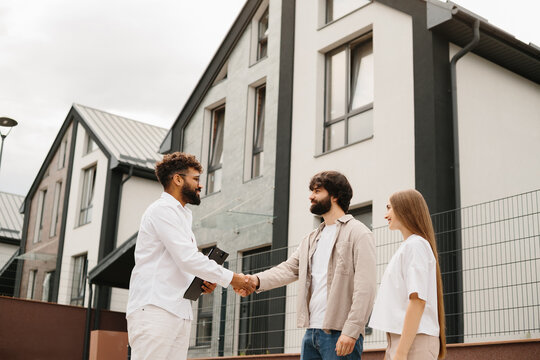 Realtor shaking hands with clients buying new home