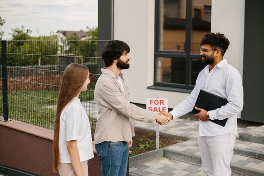 Realtor shaking hand with male client for real estate deal