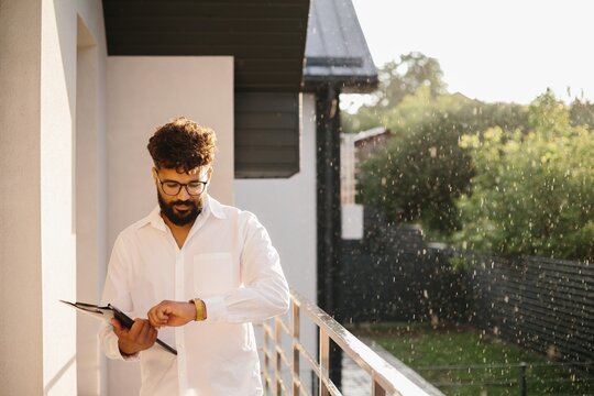 Realtor man checking watch on modern balcony