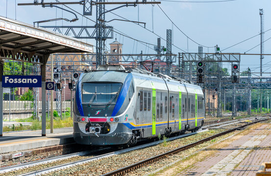 Fossano, Italy &mdash; July 30, 2026: modern Trenitalia Jazz ETR 425 commuter train showing its red tail lights as it departs from the Fossano railway station in Piedmont, Italy, under a green signal.