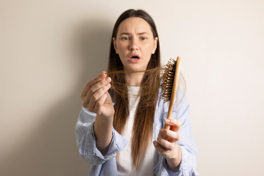 Woman concerned about hair loss holding hairbrush with fallen hair