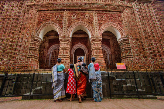 Dinajpur District, Rangpur Division, Bangladesh - 11 August 2019: View of Kantajew Temple with women and a girl in traditional saris standing before the intricate terracotta facade.