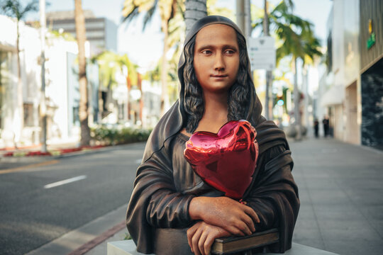 Beverly Hills, California, United States - 15 March 2026: View of a statue resembling the Mona Lisa holding a red heart-shaped balloon on the sidewalk of Rodeo Drive.