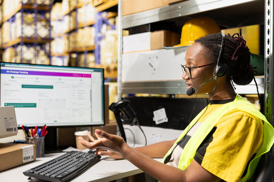 An African American woman answers calls from people in a logistics hub, handling order mix-up problems and requests via customer service helpline.