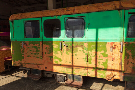 Panevezys, Lithuania - 19 September 2020: View of the weathered green and orange carriage of the Aukstaitija narrow gauge railway parked inside a depot.