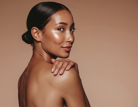Elegant woman with glowing skin and sleek bun in studio beauty portrait