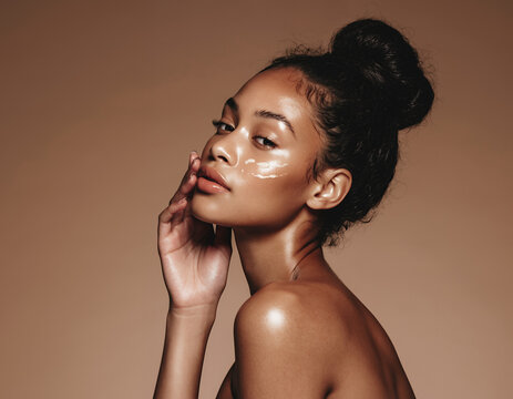 Portrait of a beautiful woman with glowing skin and facial moisturizer