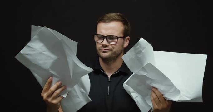 A confused man reviews several sheets of paper and shakes his head in frustration. Concept of paperwork, administrative stress, financial problems, and difficult decisions.