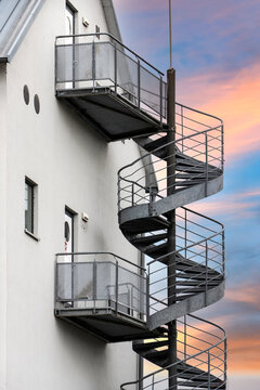 Metal Fire Escape Staircase on Building Exterior Against Sunset Sky