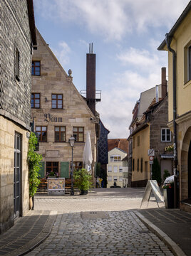 Furth, Germany - 15 July 2026: View of the historic old town with cobblestone streets, traditional stone buildings, and a restaurant terrace under a cloudy sky.