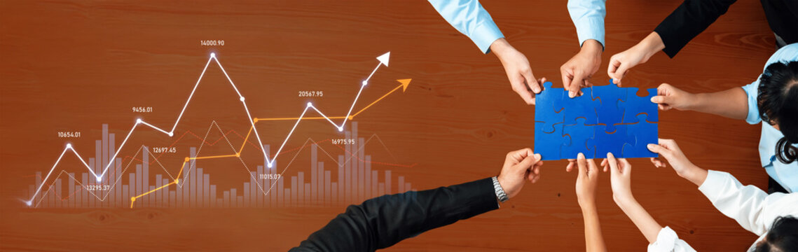 Aerial view of diverse professionals collaborating over a blue puzzle on wooden table. Graph illustrating growth and teamwork highlights strategic planning in an office environment. Scalp