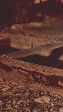 A wooden structure is seen on the ground at night. The area is dimly lit and features some stones nearby. The structure shows signs of wear and age.