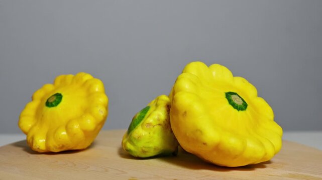 Yellow Pattypan Squash Rotating on Wooden Board