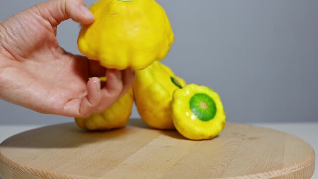 Hands Slicing Fresh Yellow Pattypan Squash on Wooden Board