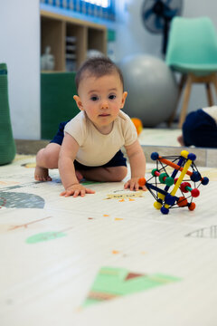 Cute baby crawling on play mat exploring a toy