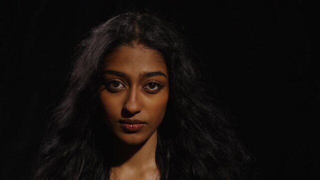 Close-up portrait of young woman with intense gaze against a dark background