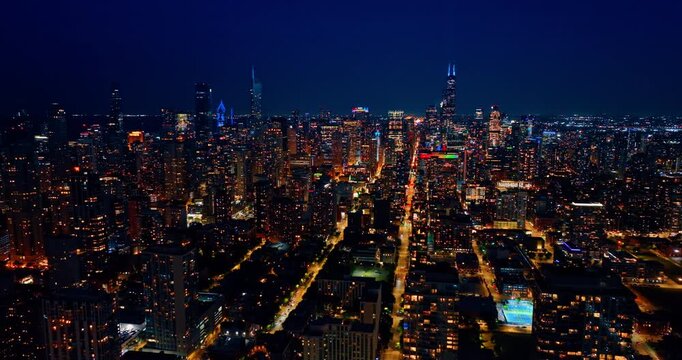 Flight over the luminous panorama of Chicago, Illinois, USA at night. Vibrant scenery of city downtown with beautiful lights.