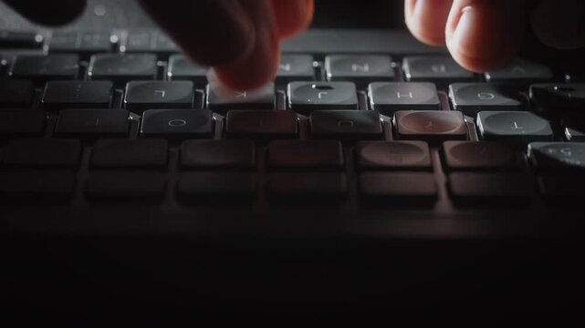 Close-up male hands typing on black keyboard, cinematic shot camera smoothly slides parallel to keys. Detailed footage of remote work, business communication, digital workflow indoors at night