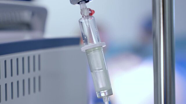 Saline solution drips in the drop counter. Close up. Medical equipment concept. Blurred backdrop.