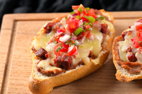 Delicious homemade Mexican molletes with spicy salsa on wooden board