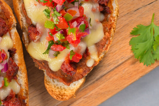 Close-up homemade Mexican molletes with refried beans, melted cheese, chorizo and fresh salsa pico de gallo