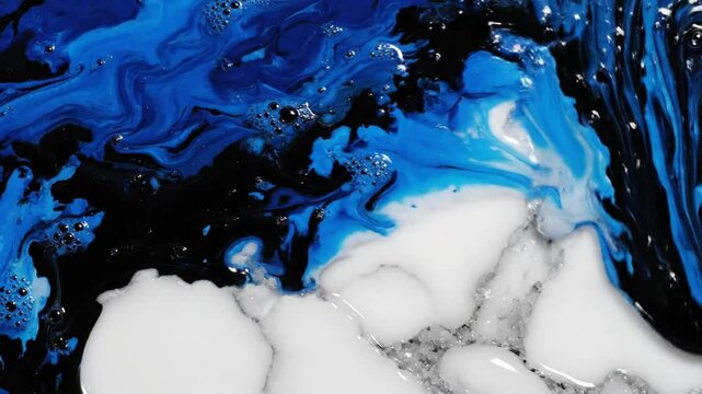 Fluid art close-up of blue and black swirling paint with white and silver texture, abstract design