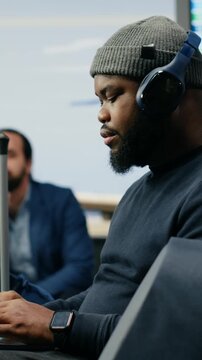 Vertical video: A Black entrepreneur works on a laptop in an airport lounge while waiting for departure, representing informal corporate culture and a business-without-suit lifestyle on a global trip.
