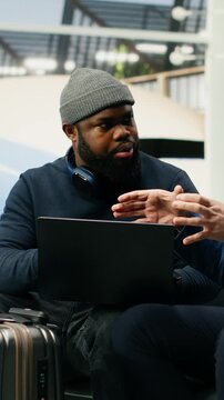 Vertical screen: A manager and assistant use a laptop at the airport while preparing for a meeting abroad and a multinational company event at headquarters.
